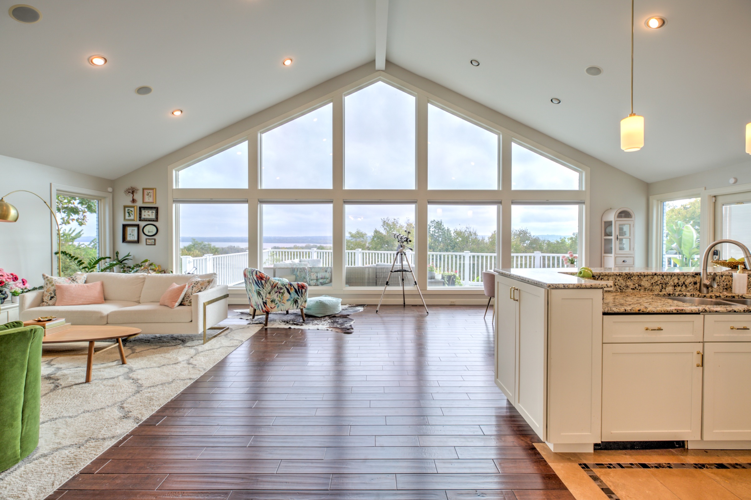 Open kitchen and living area beneath a vaulted ceiling with a dramatic wall of windows overlooking the Illinois River Valley
