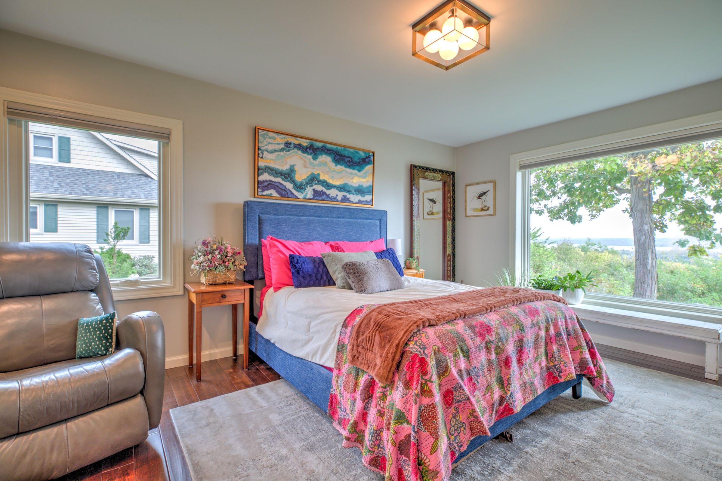 Guest bedroom with a broad picture window framing the wooded river valley view