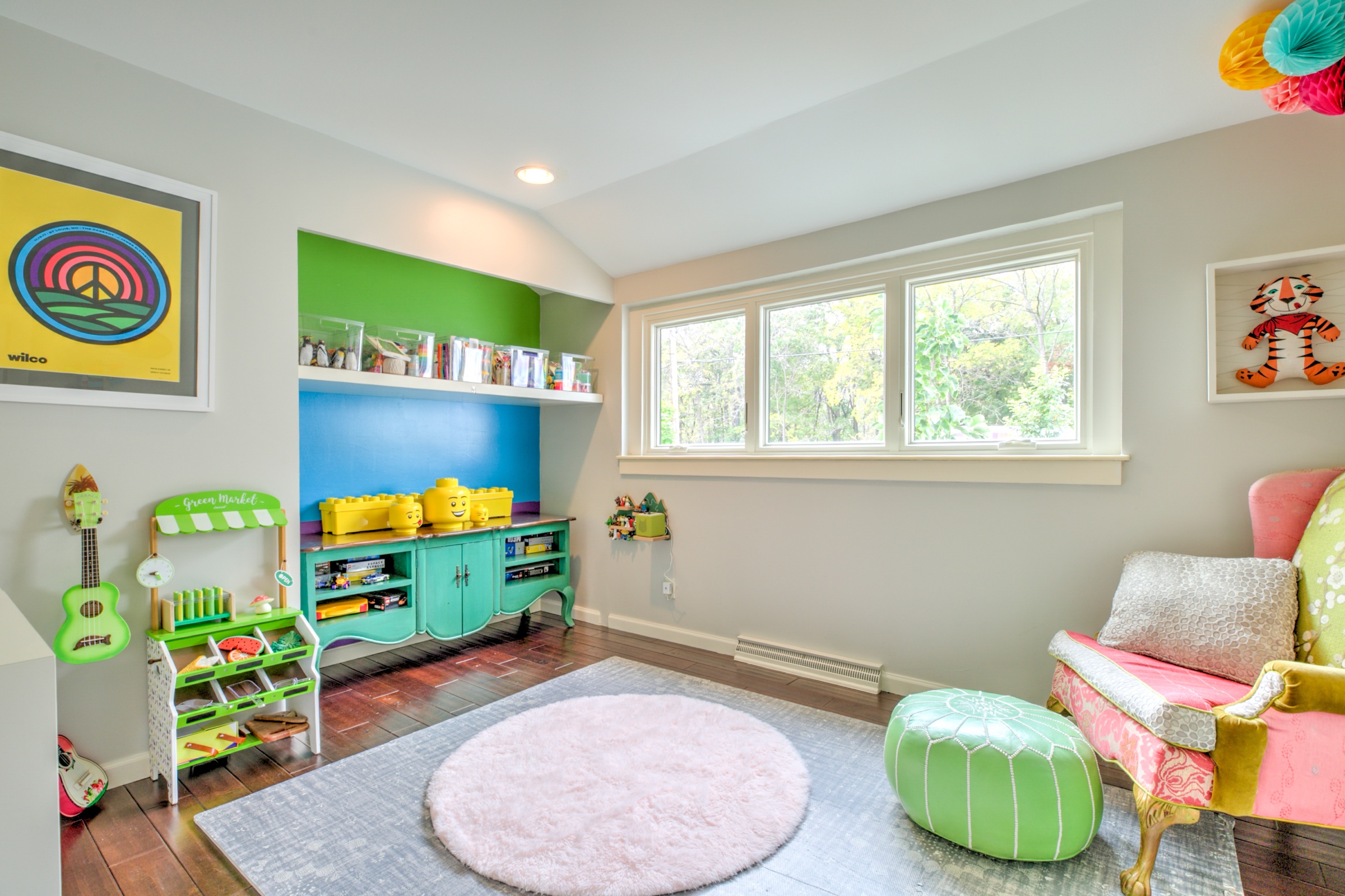 Bright flexible room with hardwood flooring, built in display ledge, and wide windows