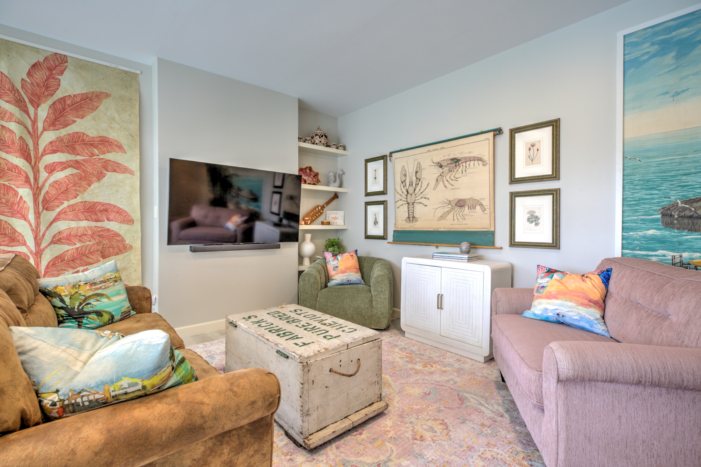 Comfortable media lounge with wall mounted television, colorful art, and casual seating